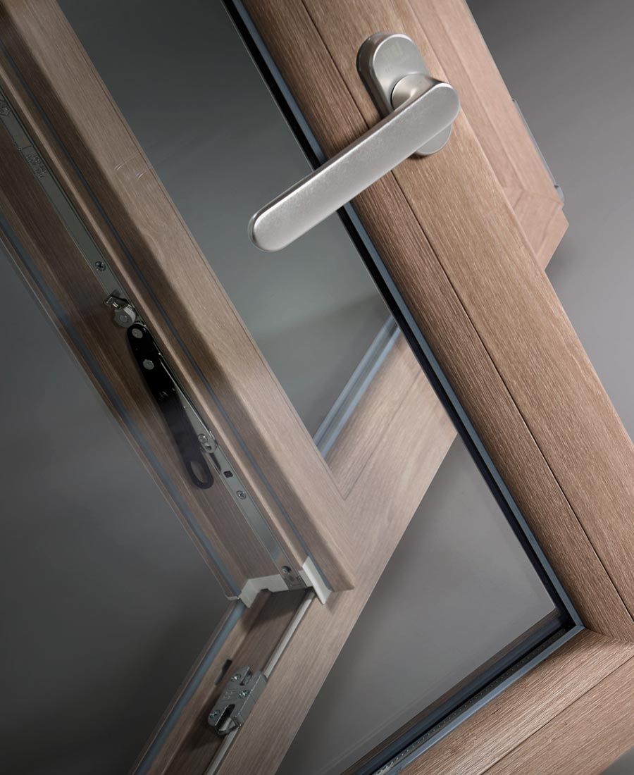 Close-up of a wood-finish window frame, handle and opening hardware