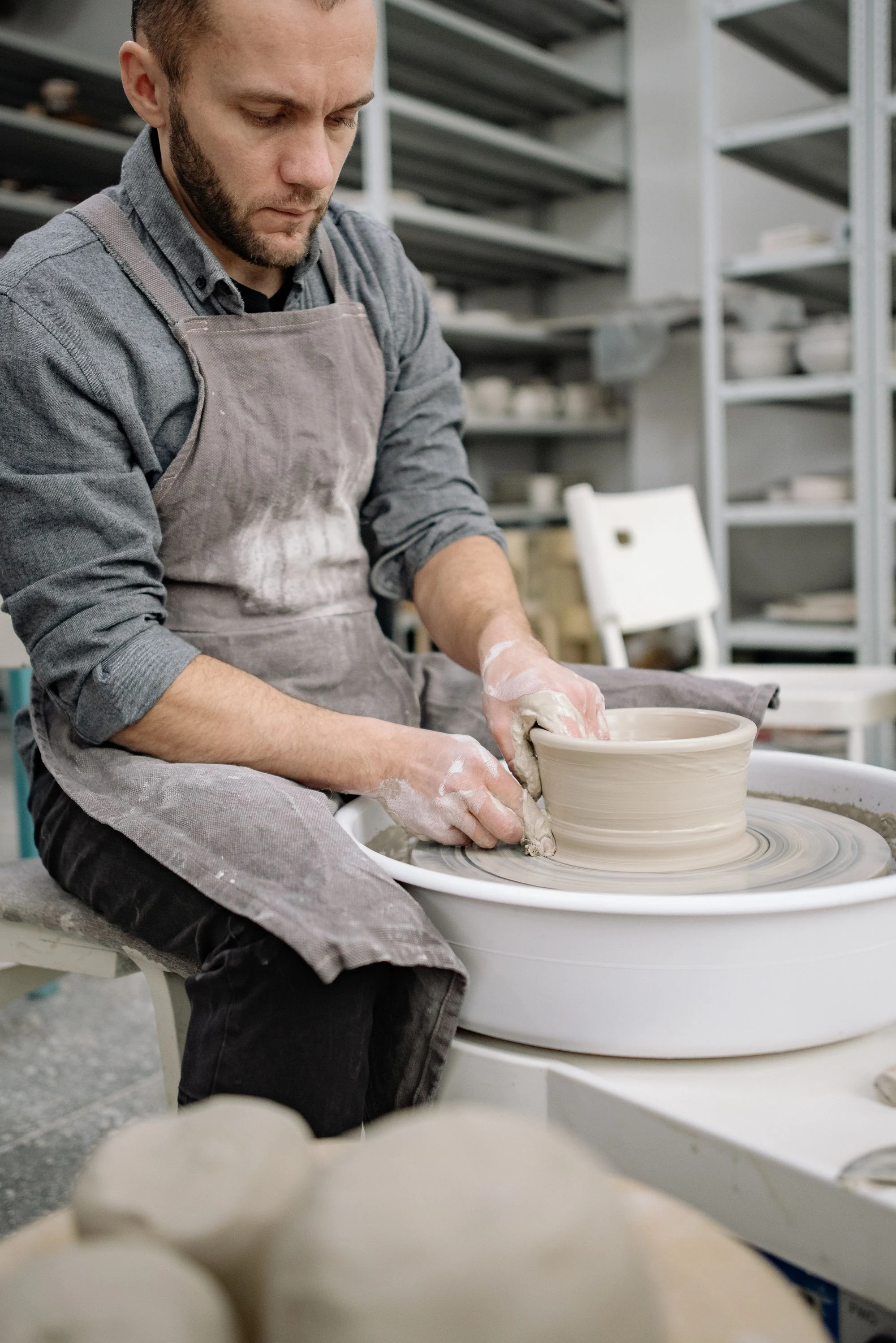 Hands shaping a ceramic vessel on a pottery wheel