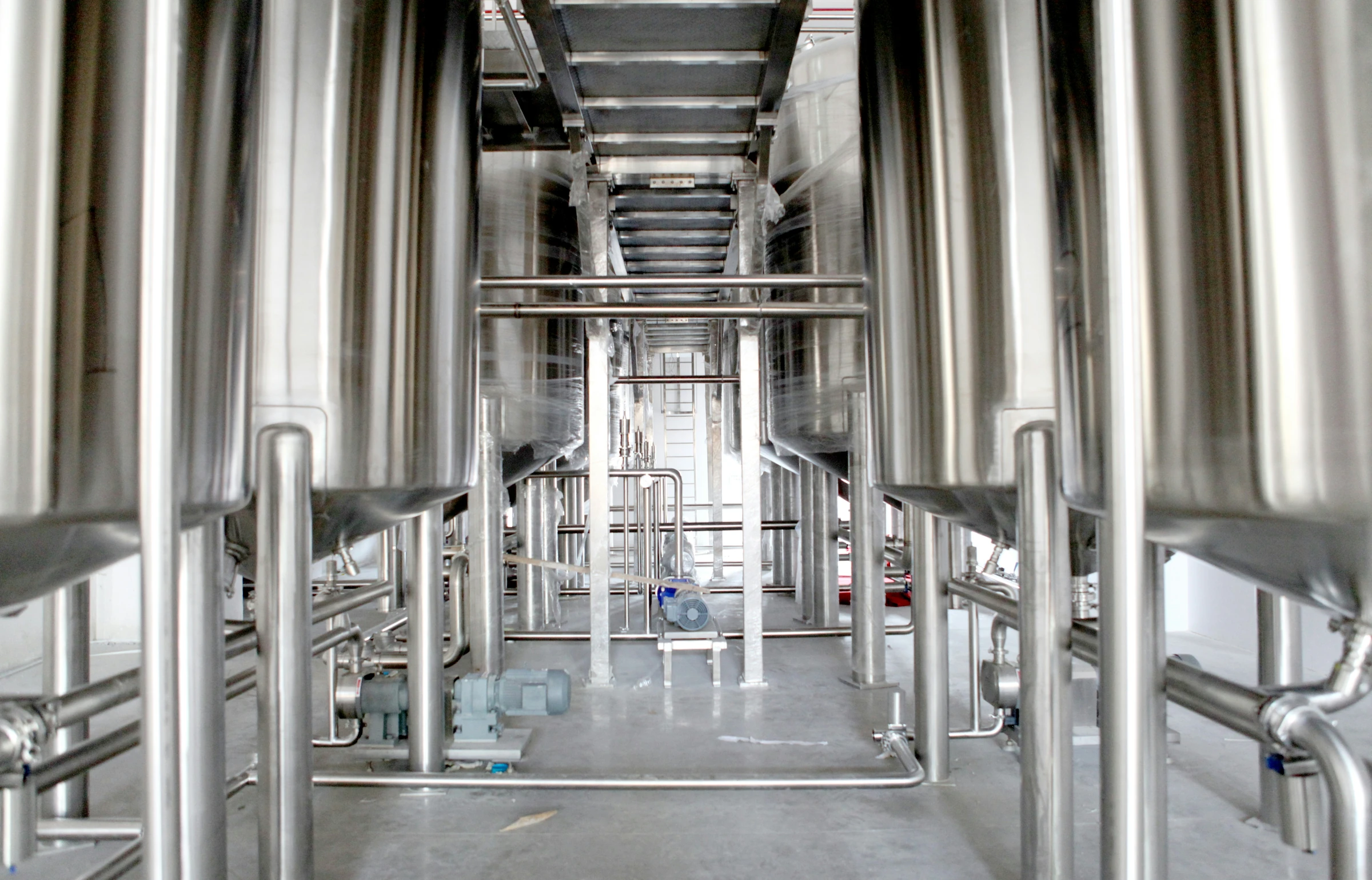 Stainless-steel processing tanks and connecting pipework inside an equipment installation